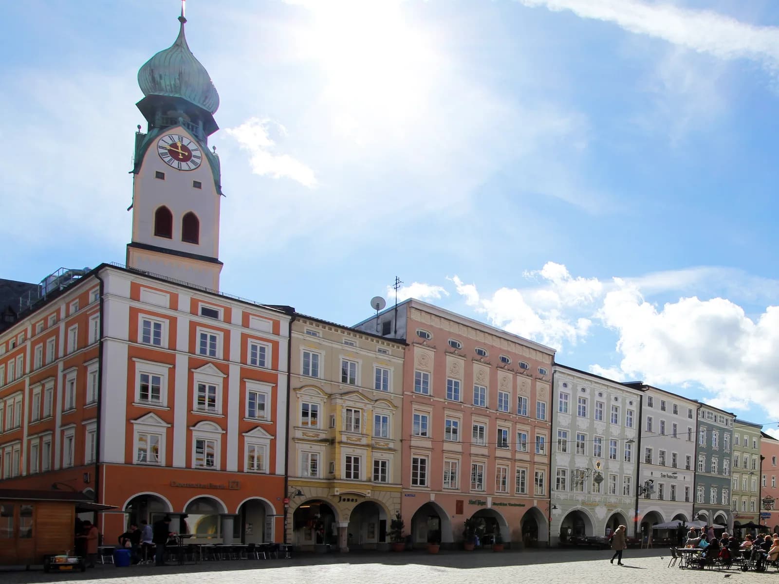 Der Max-Josefs-Platz in Rosenheim mit dem Turm von St. Nikolaus und bunten Häusern mit Arkaden